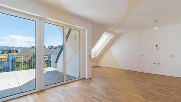 Heller Raum mit Holzboden, großen Fenstern und Zugang zu einer Terrasse, sowie einem Dachfenster.