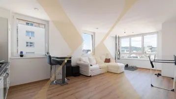 Heller offener Wohnbereich mit integrierter Küche, Laminatboden und Blick auf die Stadt.