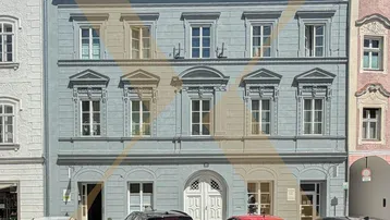 Historisches Gebäude mit blauer Fassade und klassischen Fenstern an einer Stadtstraße.