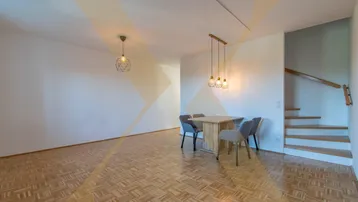Heller Wohn- und Essbereich mit Parkettboden, moderner Beleuchtung und offenem Treppenaufgang.