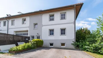 Mehrstöckiges Gebäude mit heller Fassade, Fenstern und einer Zufahrt.
