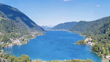 Atemberaubende Luftaufnahme eines großen Sees, umgeben von grünen Bergen und Siedlungen.