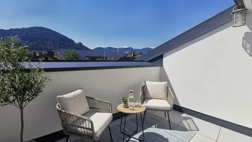 Sonniger Balkon mit bequemen Sitzmöbeln und einem weiten Blick auf die umliegenden Berge.