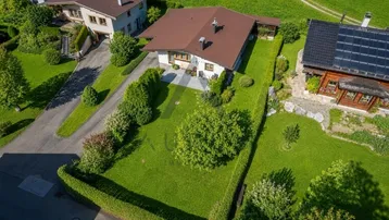 Luftaufnahme eines Einfamilienhauses mit gepflegtem Garten und Zufahrt in ländlicher Umgebung.