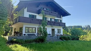 Traditionelles Haus im Alpenstil mit mehreren Balkonen, einer Terrasse und einem weitläufigen Gartenbereich.