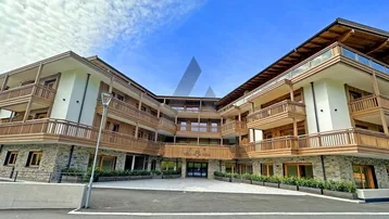 Modernes Mehrfamilienhaus mit Holz- und Steinfassade sowie zahlreichen Balkonen und gepflegtem Eingangsbereich.