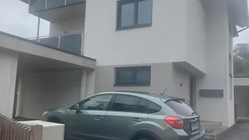 Modernes Mehrfamilienhaus mit Carport, Balkonen und gepflegter Außenanlage.