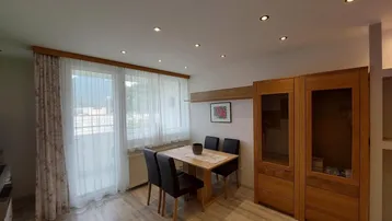 Heller Essbereich mit Holztisch, passenden Stühlen und Zugang zum Balkon mit Bergblick.