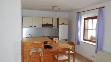 Kleine Küche mit Holzelementen, integriertem Essbereich und Fenster mit lila Vorhängen.