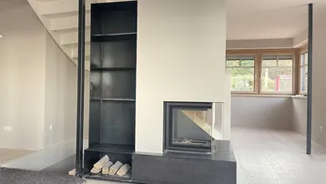 Moderner Wohnbereich mit integriertem Kamin, Holzablage und Treppenaufgang, stilvoll gestaltet.