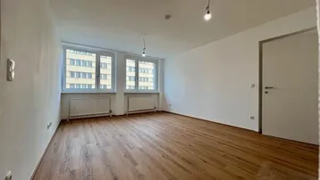 Heller, leerer Raum mit Holzfußboden und zwei Fenstern, ideal als Wohnzimmer nutzbar.