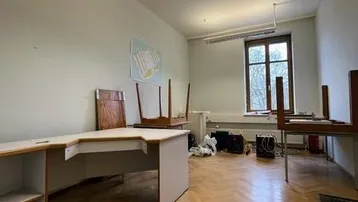 Geräumiger Büroraum mit klassischem Fischgrätparkett, großen Fenstern und funktionaler Beleuchtung, bereit zur Einrichtung.