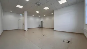 Geräumiger, leerer Büroraum mit hellen Wänden, modularem Deckensystem und funktionaler Beleuchtung.