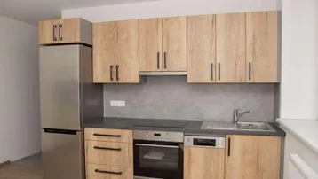 Moderne Einbauküche mit Holzoptikfronten, Edelstahlgeräten und Laminatboden.