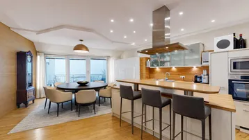 Offener Wohn-Essbereich mit moderner Küche, Holzboden und Zugang zu einem Balkon.