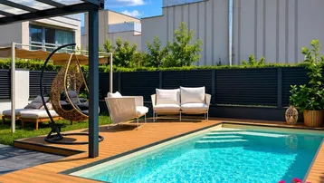 Entspannender Gartenbereich mit Swimmingpool, Holzdeck und bequemen Lounge-Möbeln.