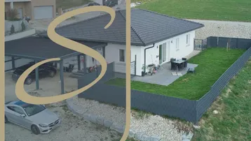 Luftaufnahme eines modernen Neubau-Einfamilienhauses mit gepflegtem Garten, Terrasse und Carport.
