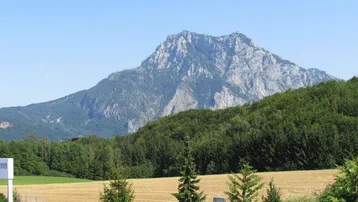 Beeindruckender Blick auf eine majestätische Bergkette, umgeben von Wäldern und Feldern.