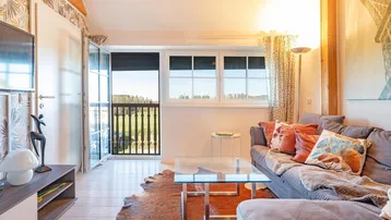 Sonniges Wohnzimmer mit gemütlicher Couch, Holzbalkendecke und Zugang zu einem französischen Balkon.