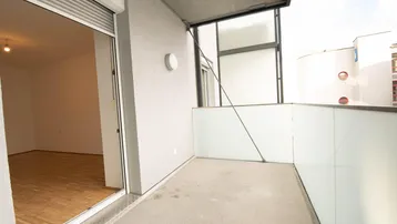 Geräumiger Balkon mit Blick in einen hellen Raum mit Parkettboden, ideal für entspannte Stunden im Freien.