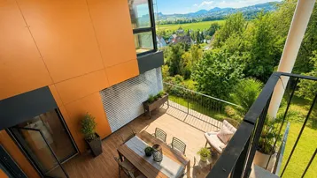 Geräumige Terrasse mit Essbereich und weitem Blick über die grüne Landschaft und Berge.