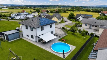Luftaufnahme des Einfamilienhauses mit Garten, Pool und Photovoltaikanlage in ländlicher Umgebung.
