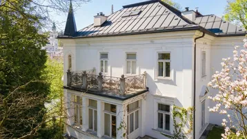 Nahaufnahme der eleganten weißen Villa mit schmiedeeisernem Balkon und klassischer Architektur.