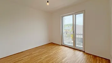Weiteres helles Schlafzimmer mit Parkettboden und einem Fenster mit Blick ins Grüne.