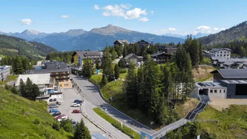 Panoramablick auf ein Bergdorf mit Hotels und Skipisten in den österreichischen Alpen.
