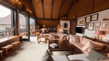 Geräumiger Wohn-Essbereich mit Holzbalkendecke, gemütlichen Sofas und Zugang zu einem Außenbereich.
