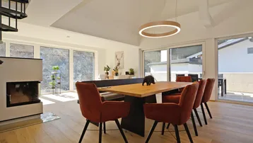 Eleganter Essbereich mit großem Holztisch, Kamin und Zugang zu einer Außenterrasse.