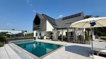 Modernes Haus mit Pool, Photovoltaikanlage auf dem Dach und großzügiger Terrasse.