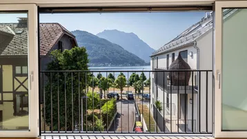 Heller Innenraum mit Holzboden und weitem Blick auf den See und die Berge.