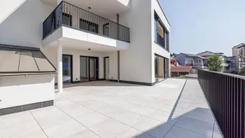 Große, helle Terrasse mit modernen Fliesen und schwarzem Geländer, ideal für Entspannung im Freien.
