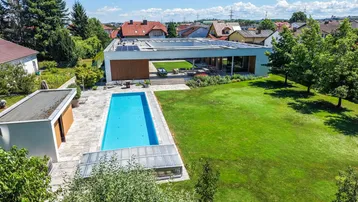 Luftaufnahme des modernen Anwesens mit großem Pool, weitläufigem Garten und umliegender Wohnbebauung.
