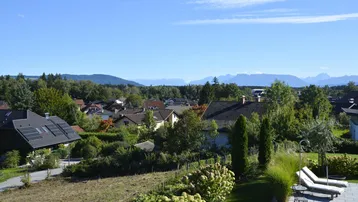 Weitläufiger Blick über die umliegende Wohnsiedlung und die Alpen am Horizont.