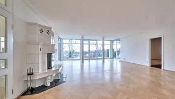Helles, geräumiges Wohnzimmer mit traditionellem Kachelofen und großen Panoramafenstern.