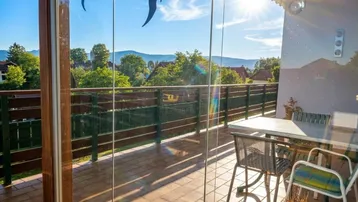 Verglaster Balkon mit weitem Blick auf die umliegende Landschaft und Berge.