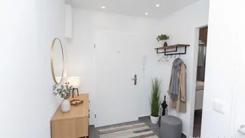 Moderner Eingangsbereich mit heller Einrichtung, Spiegel und Garderobe, einladend gestaltet.