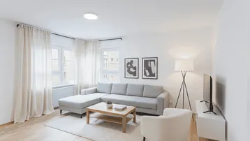 Helles Wohnzimmer mit modernem Sofa, Holztisch und großen Fenstern, als Einrichtungsbeispiel dargestellt.