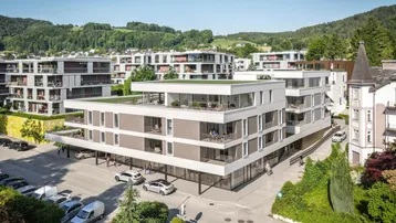 Moderne Neubauten mit Flachdächern und begrünten Terrassen in hügeliger Umgebung.
