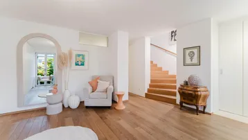 Heller Eingangsbereich mit Holztreppe, Parkettboden und einem großen Spiegel.