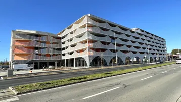 Modernes Gebäude mit wellenförmigen Balkonfassaden und großen Fenstern an einer Straße.