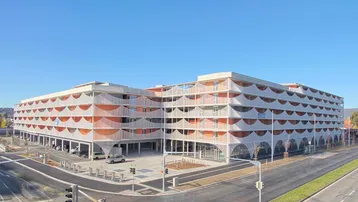 Modernes Mehrfamilienhaus mit markanter Fassadengestaltung und zahlreichen Balkonen an einer Straßenecke.