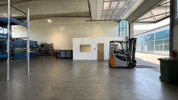 Geräumige Lagerhalle mit Betonboden, hohen Decken und einem Gabelstapler, bereit für den Betrieb.