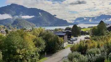 Panoramablick auf einen malerischen See, umgeben von majestätischen Bergen und einer charmanten Siedlung.