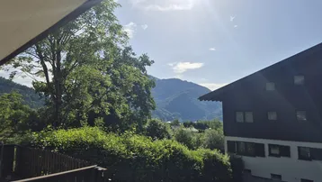 Sonniger Ausblick auf die Berge und grüne Landschaft von einem Balkon.
