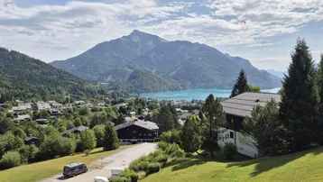 Panoramablick auf einen malerischen See, majestätische Berge und ein charmantes Dorf mit traditionellen Häusern.