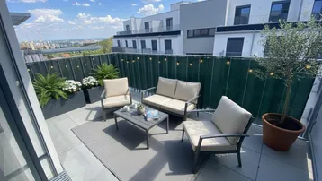 Sonnige Terrasse mit bequemen Gartenmöbeln, Pflanzen und weitem Blick über die Stadt.