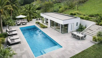 Moderne Villa mit großem Swimmingpool, Sonnenterrasse und üppiger Vegetation in einer hügeligen Landschaft.
